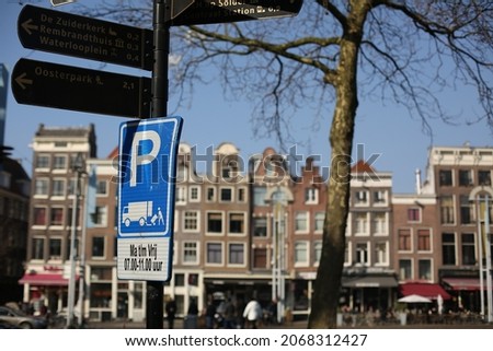 traditional brick houses and a blue parking sign on the street of amsterdam