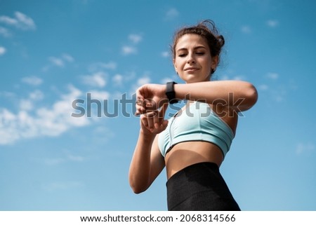 The athlete watches cardio, fitness in the city. A woman looks at sports and counts calories during training.  Exercise coach on the street, healthy lifestyle.