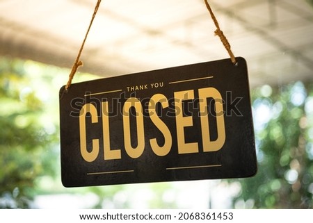 Vintage style wooden "Close" signboard which is hanging by rope of a coffee cafe shop, with blurred bokeh background. Close-up and partial focus on the text. Business sign object photo.