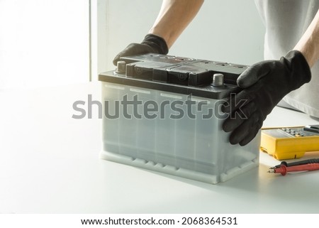 Auto mechanic checking car battery on blurred multimeter on background. Royalty-Free Stock Photo #2068364531