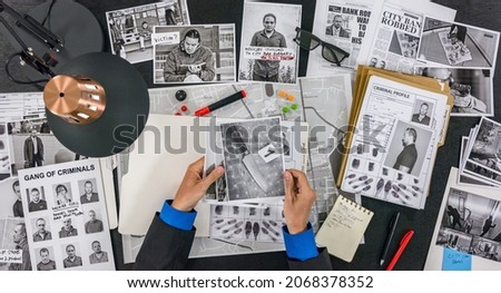 Police looking photos, documents and physical evidence. View from above. Royalty-Free Stock Photo #2068378352