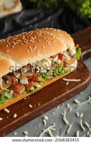 Chicken sandwich with mushrooms and mozzarella cheese and lettuce on cutting bored  