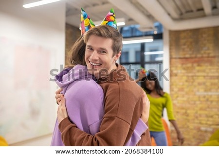 A young guy hugging his colleagues and congartulating her with her bday