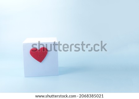 Abstract blue cube with a bright heart on a blue copy space background. Podium in the form of a cube a place for text
