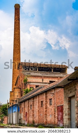 Abandoned red brick factory building and big chimney