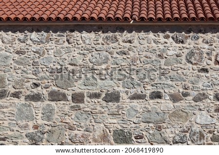 Part of an old stone wall and roof. Natural background or texture. High quality photo.
