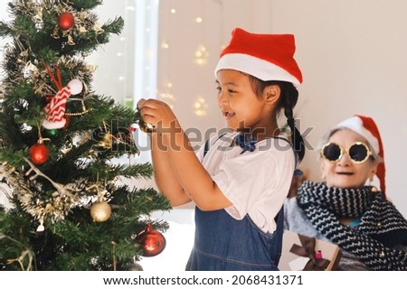 Smiling little girl decorating Christmas tree at home,Happy Christmas time concept.