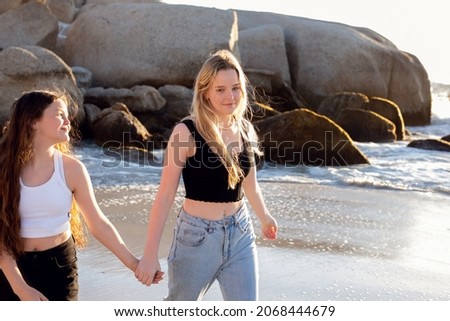 Beautiful sisters on the beach. Playful and fun. Walking and holding hands. 