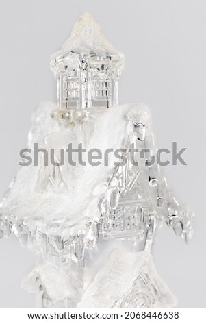 Glass christmas figurine of a house with snow. christmas Composition on gray background. Home sweet home christmas concept.