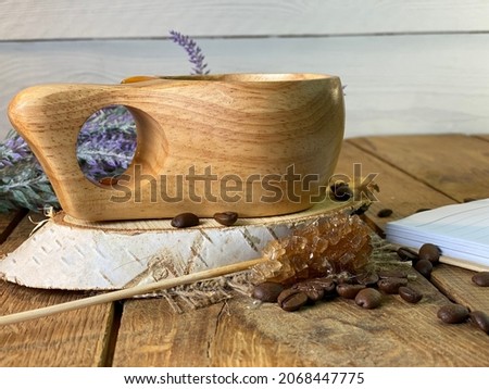 a table made of oak boards you can see jars on them there is a bouquet of lavender a wooden cup with coffee and a notebook and a pen a wall made of pine boards painted white