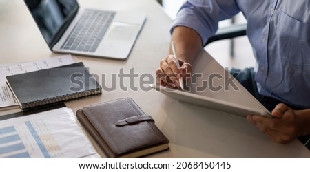 Businessman working on digital tablet marking few imports points with a stylus. Male entrepreneur checking finance report on his tablet computer
