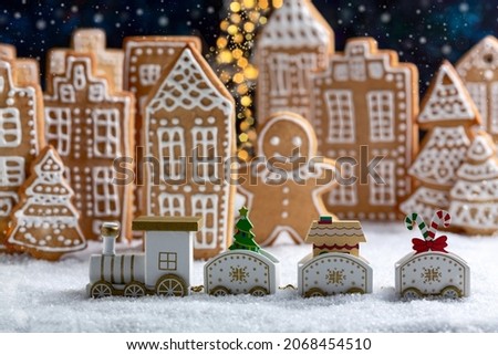 Christmas toy train in a snowy gingerbread town, selective focus. Concept of Christmas or New Year winter holidays.