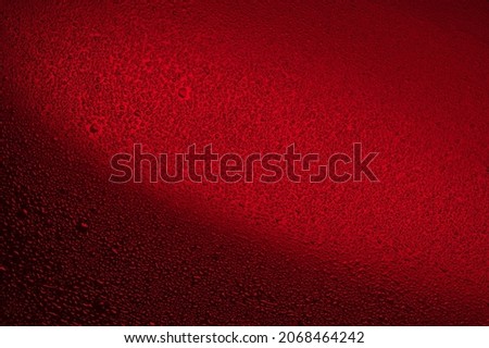 Water drops on black glass. Abstract background illuminated with red ​light.