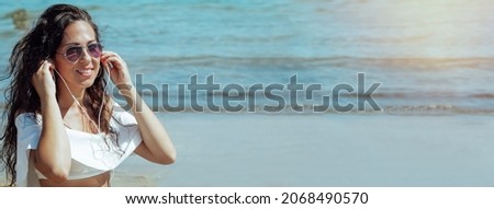 young woman on the beach with headphones listening to music