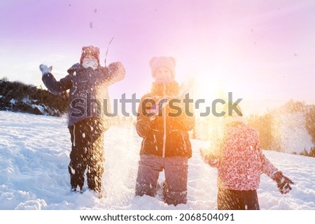 Children playing snowballs, having fun in the snow, happy winter holidays.