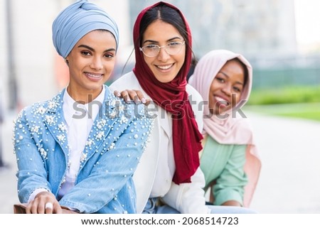 Multiethnic group of muslim girls wearing casual clothes and traditional hijab bonding and having fun outdoors - 3 arabic young girls