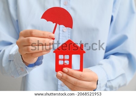 Woman with house figure and umbrella, closeup. Property insurance concept Royalty-Free Stock Photo #2068521953