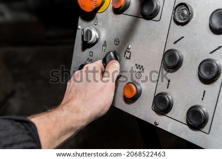 Human hand uses old control panel of industrial equipment in the factory.