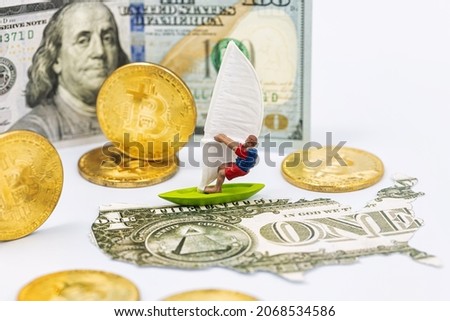 Toy windsurfer, gold bitcoins and US card from dollars