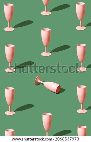 Pattern made of pink champagne glasses on a green background. New year Christmas party celebration concept
