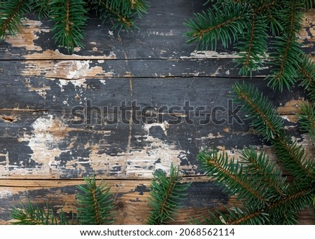 Christmas tree branches on rustic wooden background with empty space in the middle. Flat lay, top view, add text, copy space