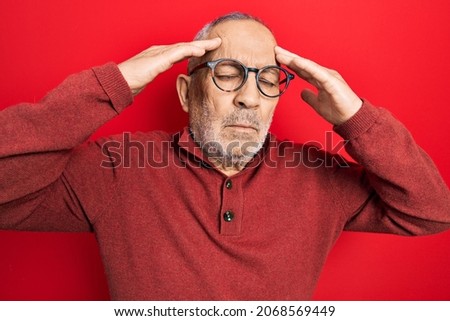 Handsome mature man wearing casual sweater and glasses with hand on head, headache because stress. suffering migraine. 
