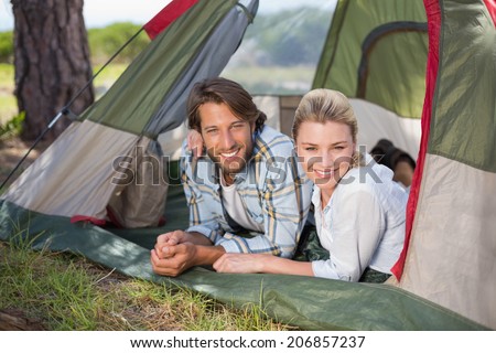 Attractive couple lying in their tent smiling at camera on a sunny day
