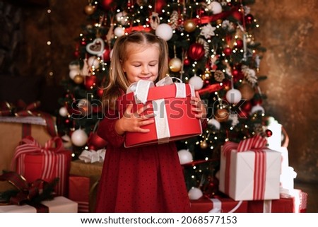 portrait of a girl at Christmas with a gift at the tree. postcard for the new year. winter holidays