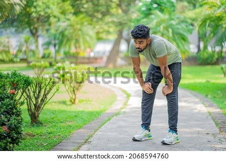 Tired young man runner taking a rest after running hard at the park Royalty-Free Stock Photo #2068594760