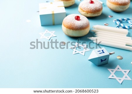 Hanukkah doughnuts sufganiyot with powdered sugar and fruit jam, gift boxes on blue paper background. Jewish holiday Hanukkah concept. Selective focus, copy space.
 Royalty-Free Stock Photo #2068600523