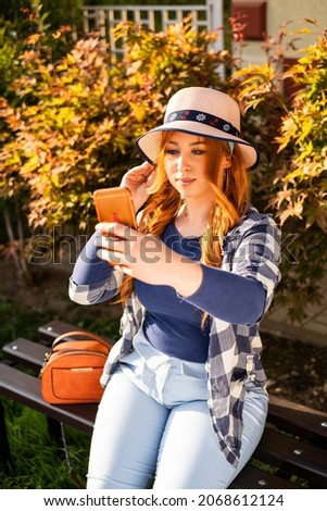 smiling orange hair girl with hat in park, take self-photo