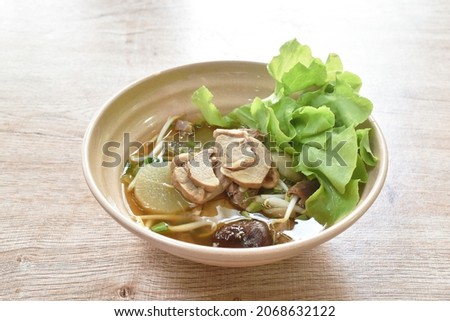 braised pork and bone with green oak in brown soup on bowl 