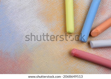 Colorful pastel chalks on abstract drawing, flat lay. Space for text
