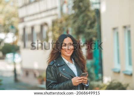 Young beautiful dark-haired woman walking in the autumn European city. Talking on the phone. Fall.