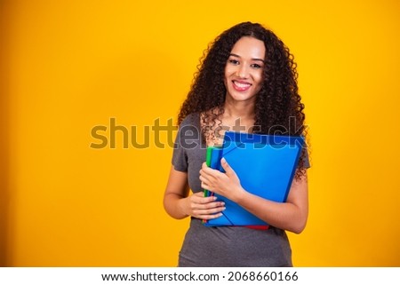 Young African-American student in yellow background. Portrait of young female university student holding notebooks on yellow background.