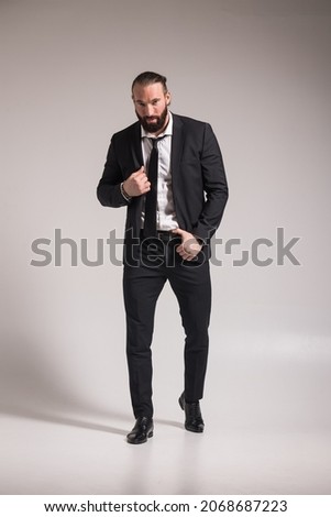 Photo of a handsome brutal man with a beard and long hair in a business suit of photography studios on a neutral background