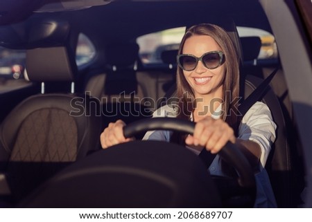 Photo portrait smiling woman wearing sunglass keeping steering wheel in the car Royalty-Free Stock Photo #2068689707