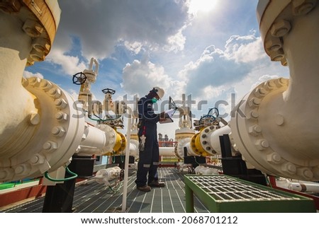 Male worker inspection at steel long pipes and pipe elbow in station oil factory during refinery valve of visual check record pipeline oil and gas industry. Royalty-Free Stock Photo #2068701212