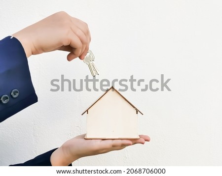 Hand giving keys and house miniature on white background. New house purchase concept.