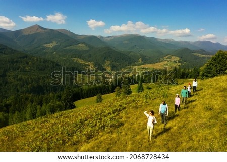 Group of tourists walking on hill in mountains. Drone photography