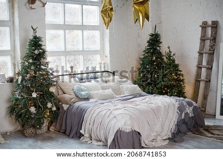 Christmas loft bedroom with big windows, Christmas decorations, Christmas trees and lights. Loft boho interior with Christmas decor