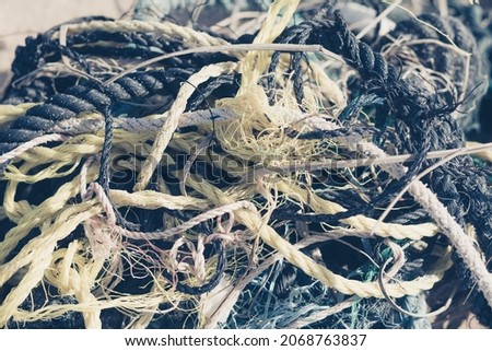 E Close multi colored black white yellow old fishing twisted cotton ropes heap pile jumble detail. Concept tangle mess mix mishmash maze, environmental protection rubbish, pale tone more in stock
