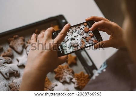 Woman takes photo on smartphone Christmas gingerbread sprinkled with powdered sugar.