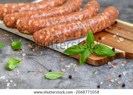 Raw pork  sausages  ready for cooking with spices  on  marble cutting board