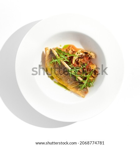 Roast white fish with vegetables isolated on white background. Grill halibut with crispy skin and tomato salad. Fish fillet with vegetables garnish in minimal style. Seafood Restaurant menu