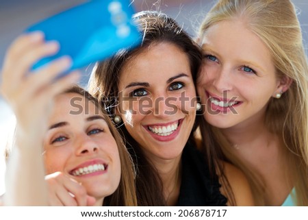 Outdoor portrait of group of friends taking selfie in the street.