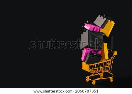 Black friday sale background. Shopping cart and shopping bags on a black background. Copy space.