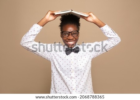 expression of an african female student with glasses with a book on her head 
