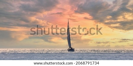 Sailboat sailing towards the horizon at sunset