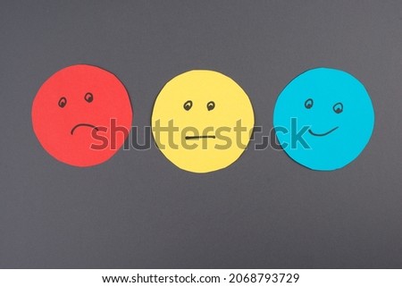 Three faces, smiling, sad in different colors on a gray background, copy space, rating, communication, customer feedback